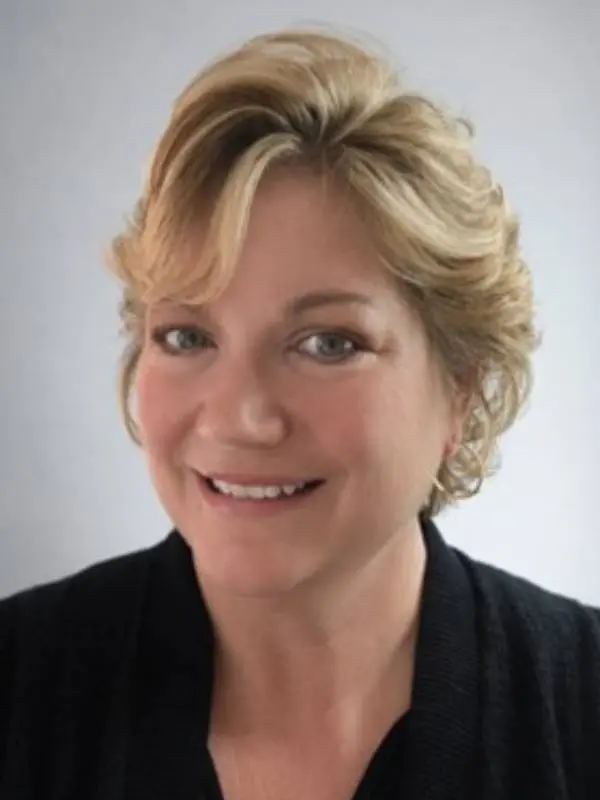 Smiling woman with short blonde hair in a black top.