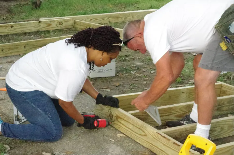 Two people working together on a wooden frame construction.