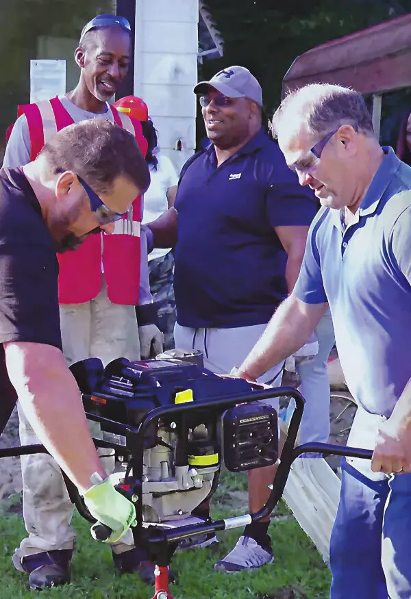 Two men operating a portable generator outdoors.