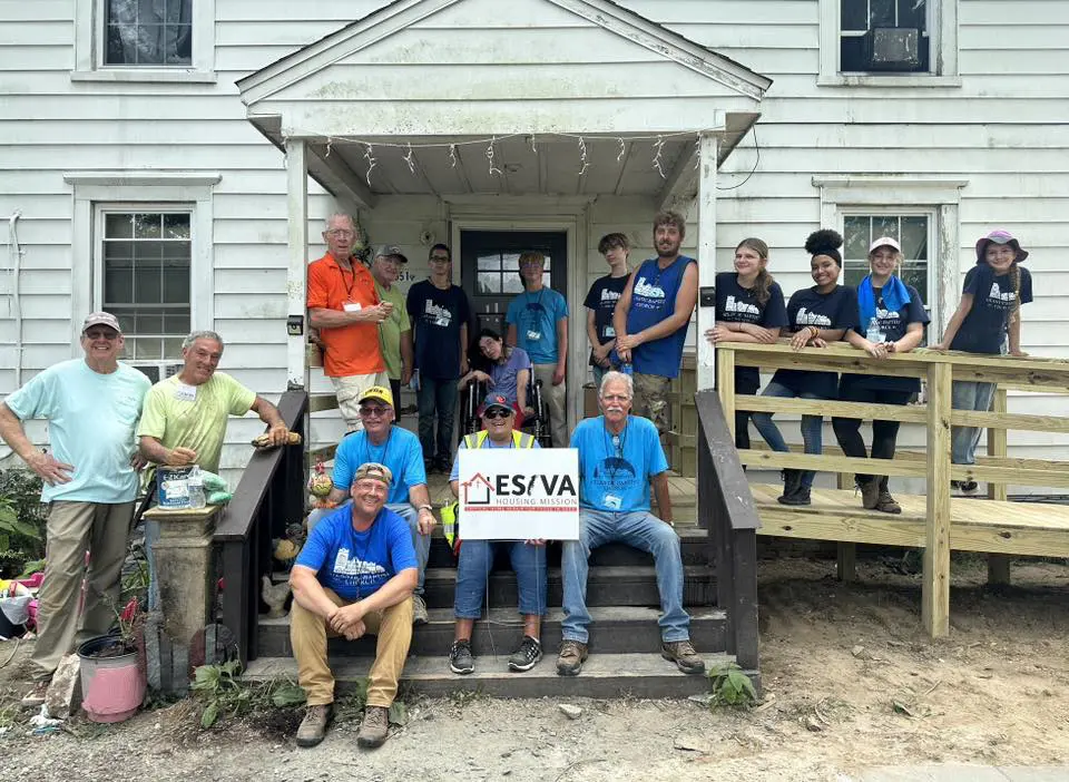 Group of volunteers posing in front of a white house under renovation.