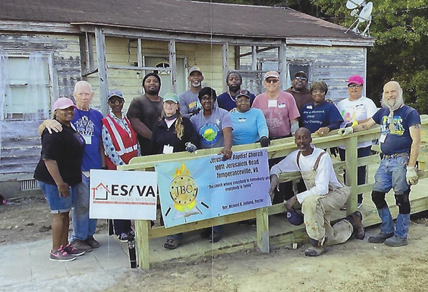 Group of people holding a banner for a community organization outdoors.