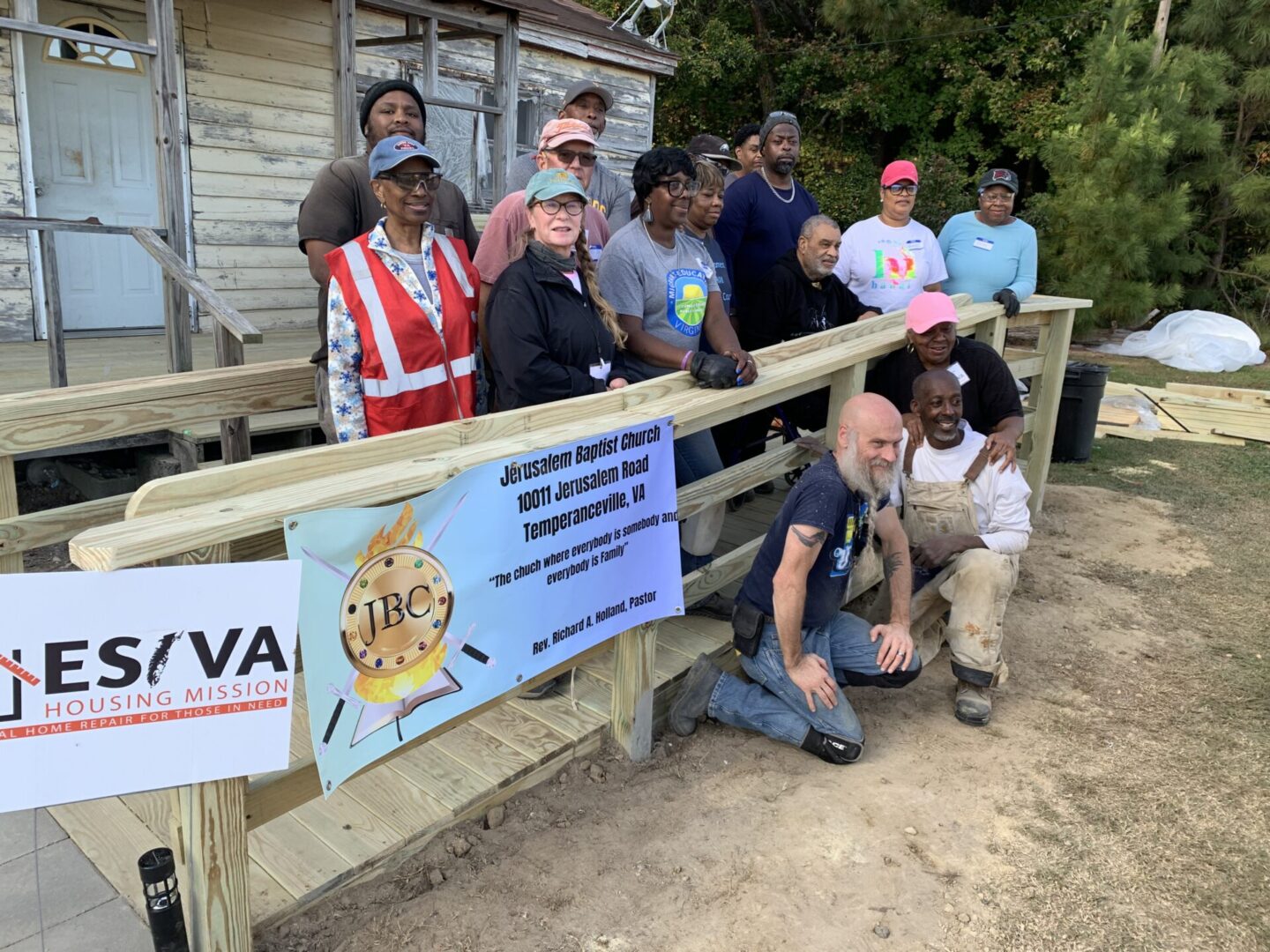 Group photo of people with a banner at an outdoor event.