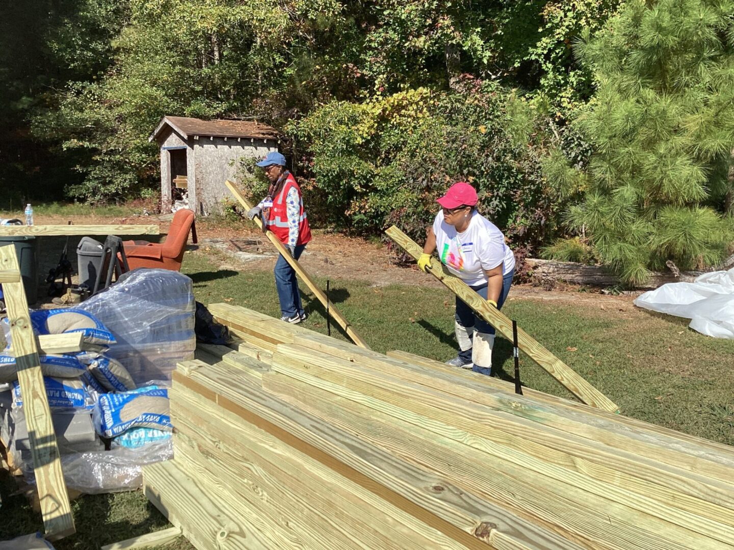 Two workers cutting wood outdoors surrounded by trees.