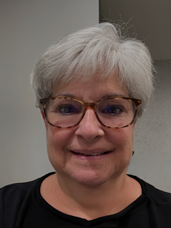 Smiling woman with short gray hair and glasses.