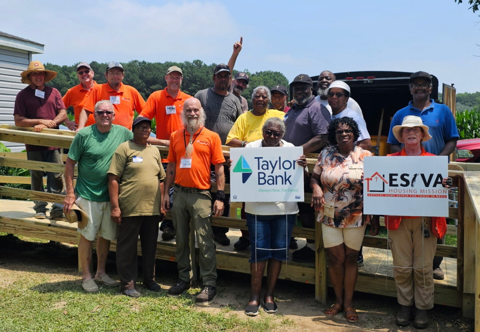 Group of people posing outdoors with a Taylor Bank sign.