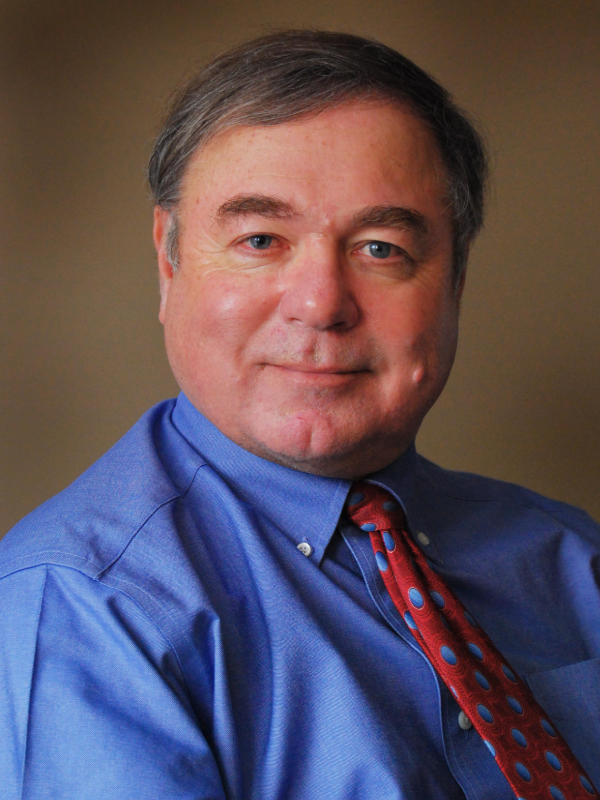 Portrait of a middle-aged man in a blue shirt and patterned tie.