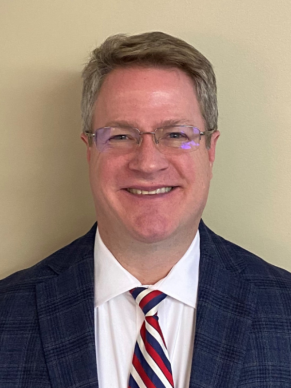 Smiling man wearing glasses and a suit with a striped tie.