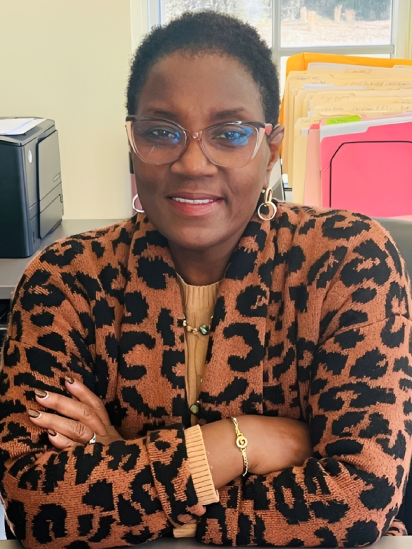 Woman in leopard print jacket smiling with arms crossed.
