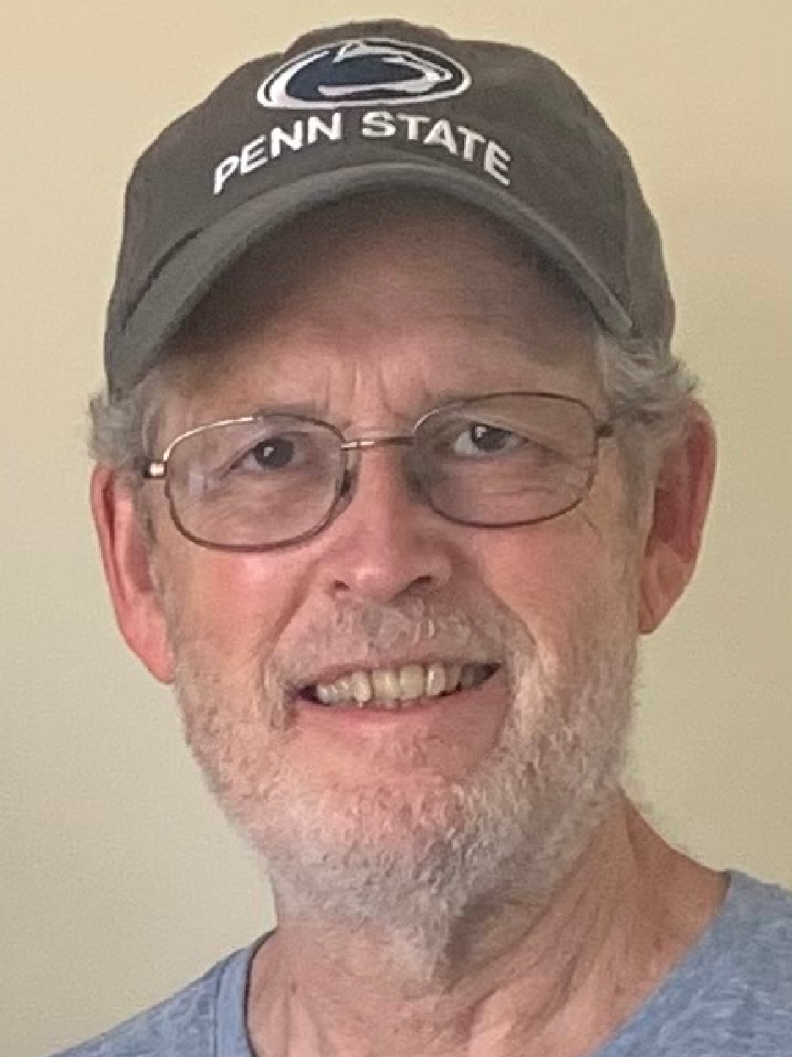 Smiling man wearing glasses and a Penn State cap.