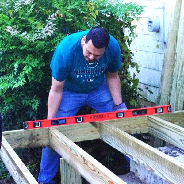 Man using a level tool on wooden beams outdoors.